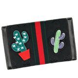 Cactus Met Witte Stekels In Rode Pot Strijk Patch samen met een andere cactus strijk patch op een zwarte portemonnee met een groen en rood lint