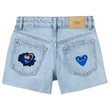 Hartje Met Oogjes Strijk Embleem Patch Donker Blauw samen met een andere hartjes patch op de achterzakken van een korte spijkerbroek