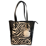 Sleutelhanger Pom Strik Strass Tas Keychain Wit aan een zwarte leren tas met zebra print