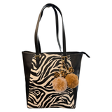 Sleutelhanger Pom Strik Strass Tas Keychain Cognac samen met de beige / crème variant aan een zwarte tas met zebraprint