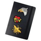 Adelaar Eagle Strijk Embleem Patch samen met een tattoo love en een goudkleurige bijen strijk patch op de voorzijde van een zwarte agenda