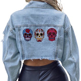 Sugar Skull Mexico Strijk Embleem Patch samen met een roze en lichtblauwe variant op de achterzijde van een spijkerjasje