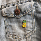 Geel met groen ananas pin met een oogje op een borstzakje van een spijkerjasje