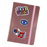 Boeddhistische Oog Strijk Embleem Patch Blauw Roze samen met twee strijk patches op de voorzijde van een glitter roze agenda