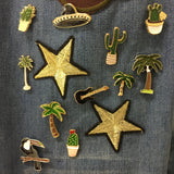 Cactus Emaille Pin In Pot samen met ander pins  op een achtergrond van spijkerstof