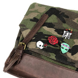 Emaille Pin Van Groen Alien Hoofd Met Bloemen Krans samen met drie nadere pins op een groen canvas camouflage tas